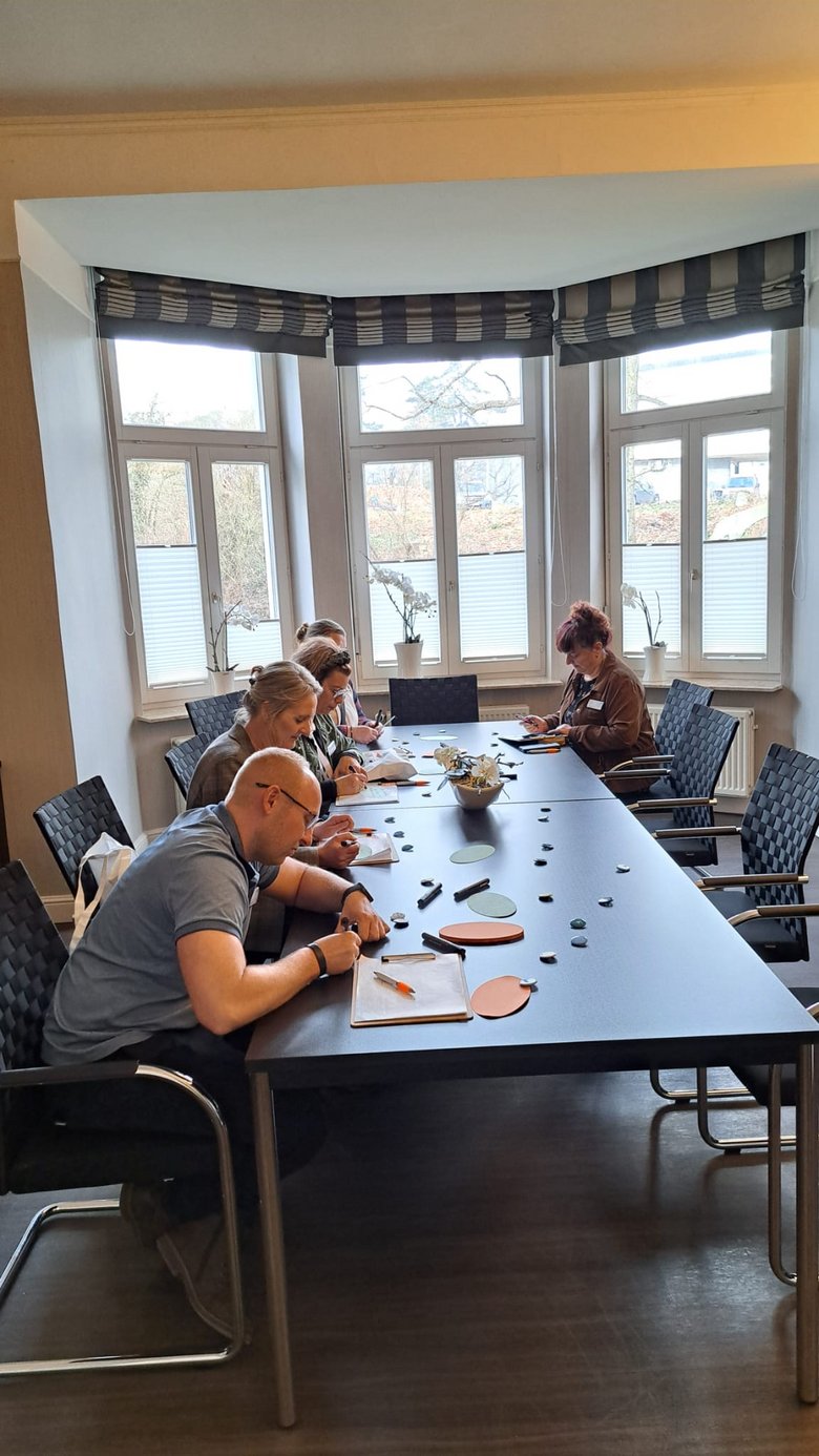 Eine kleine Gruppe arbeitet an einem großen Tisch.
