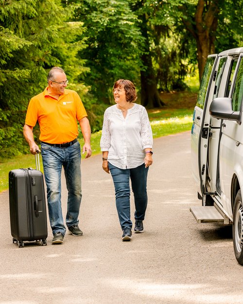 Mann und Frau gehen mit Koffer auf die Kamera hinzu