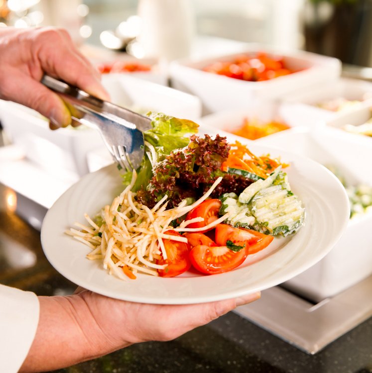 Koch richtet Salat auf einem Teller an