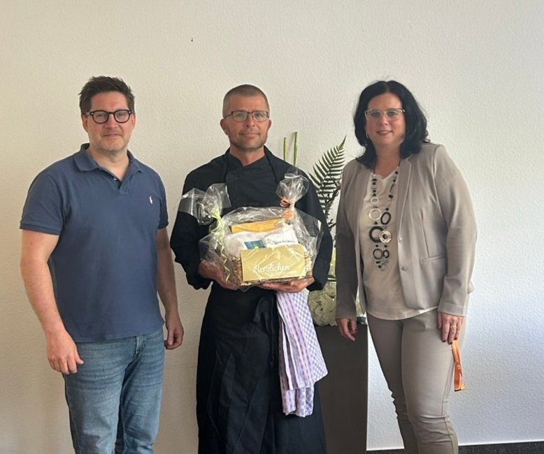 10-jähriges Jubiläum von Christian Beulich Christian Beulich steht neben Verwaltungsleiterin Anja Hölscher und Geschäftsführer Thomas Albrecht, die ihm einen Präsentkorb überreichen. Er feiert sein 10-jähriges Jubiläum in der Helenenquelle.