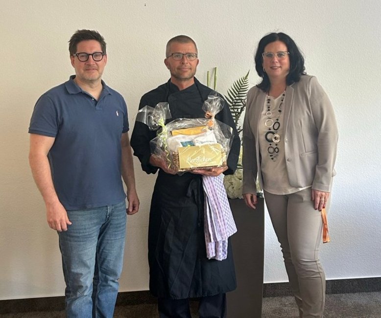 10-jähriges Jubiläum von Christian Beulich Christian Beulich steht neben Verwaltungsleiterin Anja Hölscher und Geschäftsführer Thomas Albrecht, die ihm einen Präsentkorb überreichen. Er feiert sein 10-jähriges Jubiläum in der Helenenquelle.