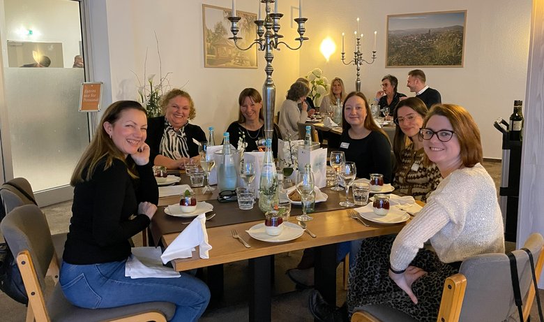 Verschiedene Personen sitzen um festlich gedeckte Tische 