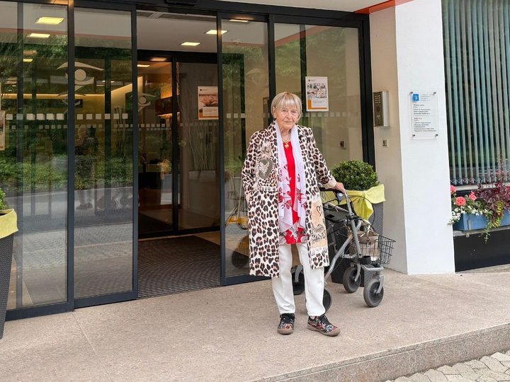 Renate Vehovsky in der Helenenquelle Renate Vehovsky lächelt in die Kamera während sie vor dem Eingang der Helenenquelle steht.