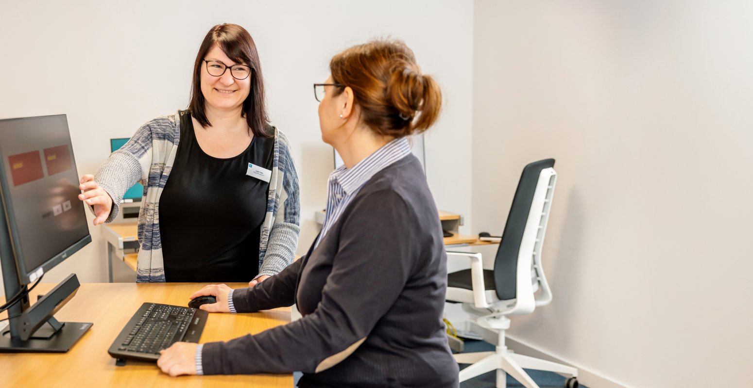 Zwei Frauen stehen an einem Schreibtisch und reden