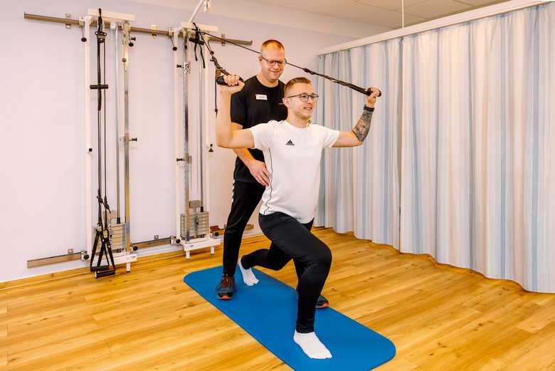 Physiotherapeut begleitet Rehabilitand beim Krafttraining