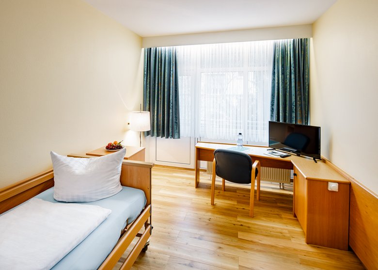 Zimmer mit Einzelbett, Schreibtisch und TV