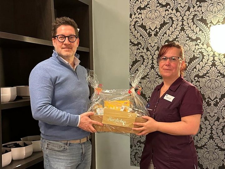 Madeleine Tomaske aus der Ernährungsberatung steht neben Geschäftsführer Thomas Albrecht, der ihr persönlich einen Präsentkorb überreicht. Sie feiert ihr 25-jähriges Jubiläum bei den ZEISS KLINIKEN.
