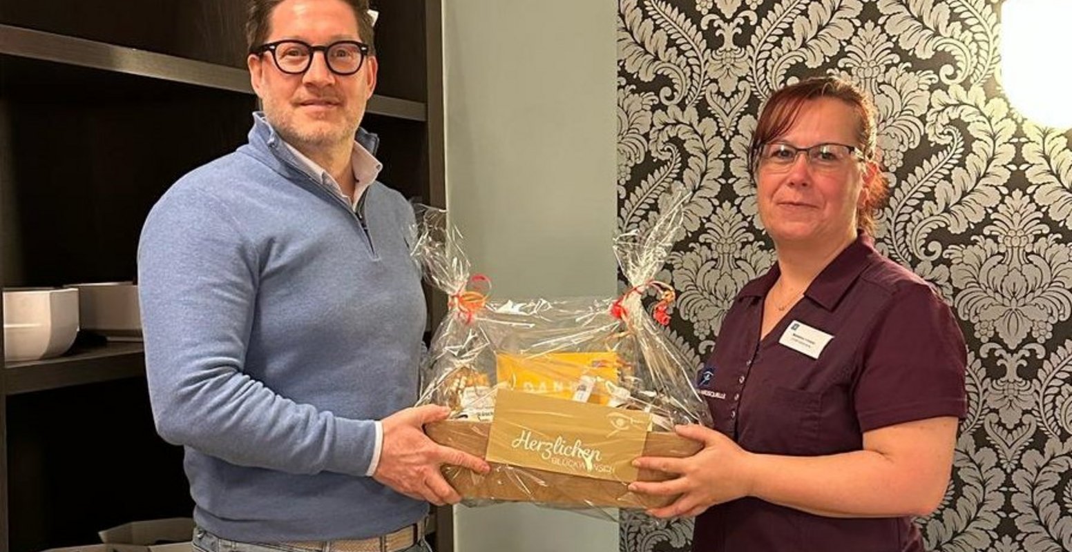 Madeleine Tomaske aus der Ernährungsberatung steht neben Geschäftsführer Thomas Albrecht, der ihr persönlich einen Präsentkorb überreicht. Sie feiert ihr 25-jähriges Jubiläum bei den ZEISS KLINIKEN.