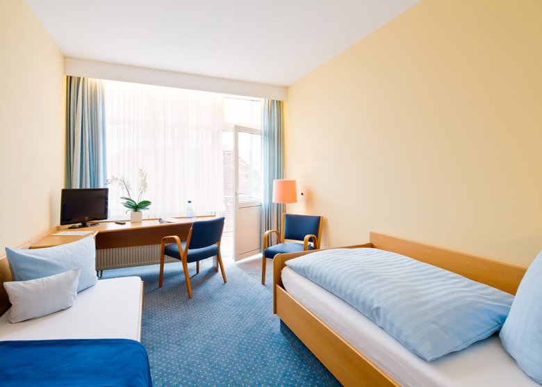 Zimmer mit Einzelbett, Schreibtisch und TV