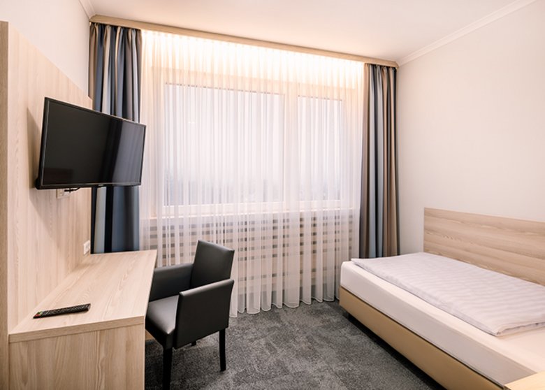 Zimmer mit Einzelbett, Schreibtisch und TV